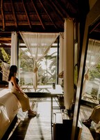 A room with a bed, a table, and a window with curtains.