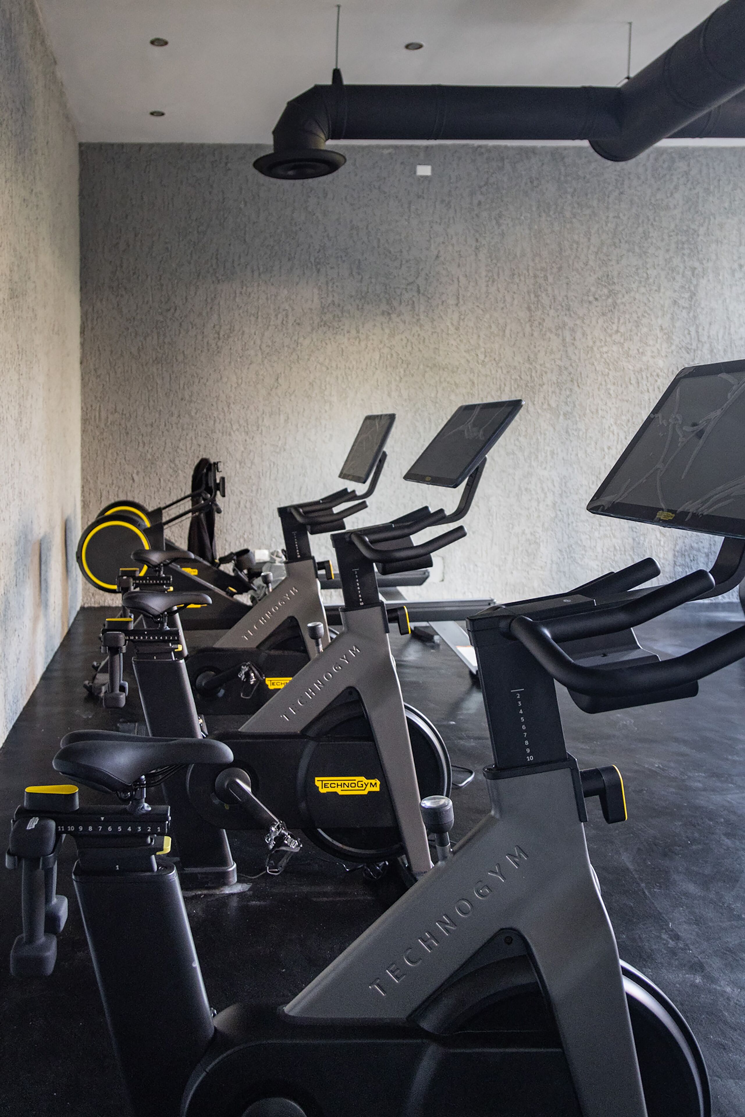 A gym with stationary bikes and elliptical machines, equipped with digital screens and resistance settings.