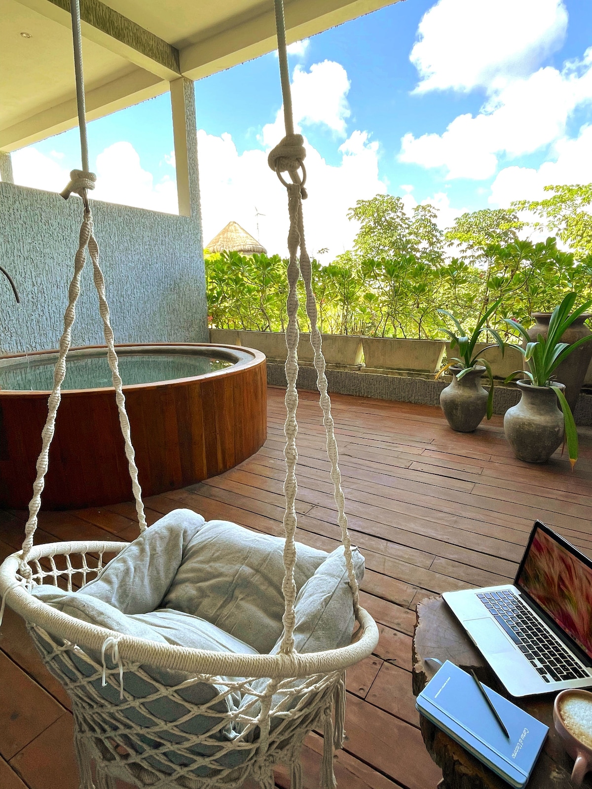 patio area of Hotel Azulito, wit circular plungo pool and boho swing, a laptop on the side table