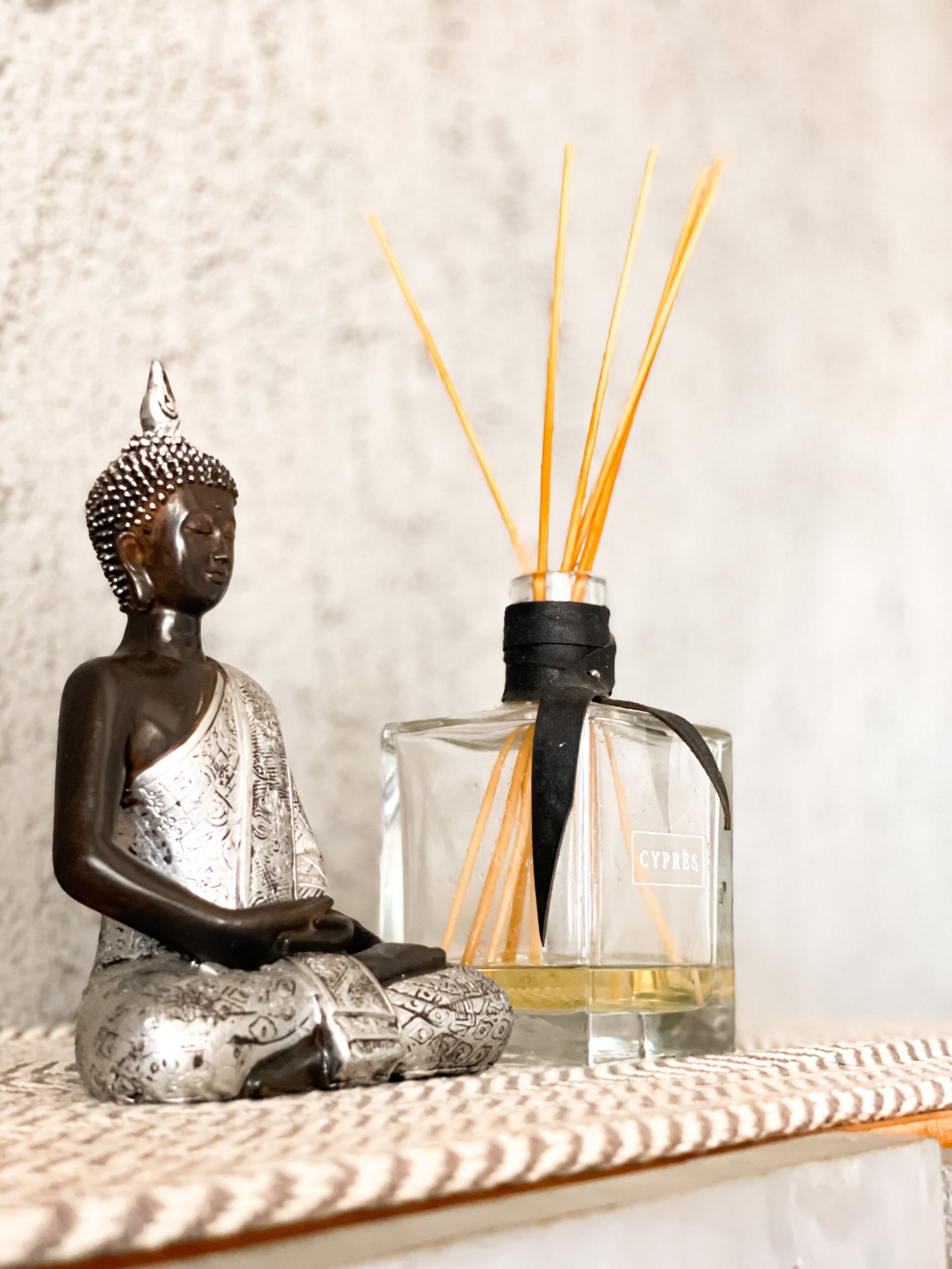 A Buddha statue and a bottle of incense with reed sticks.