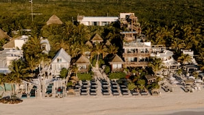 Resort com vários edifícios, praia e palmeiras.