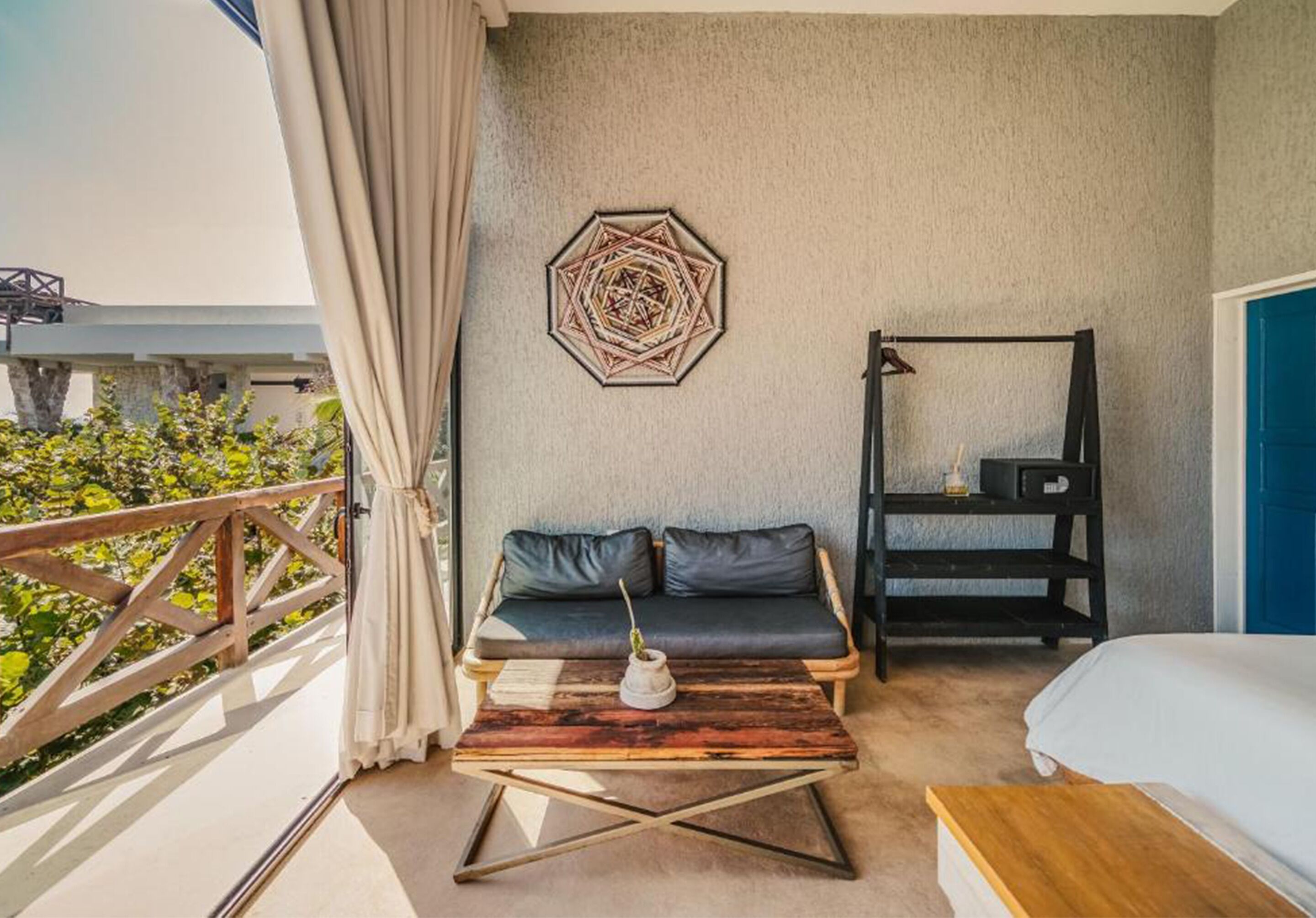 A balcony with a wooden railing, a sofa, a coffee table, a wall-mounted shelf, and a bed.