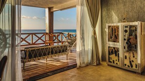 Quarto com vista para o mar, um deck de madeira e um armário com obras de arte.