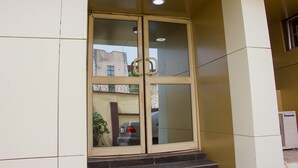 A building entrance with a glass door, a visible car parked outside, and a Panasonic air conditioner on the right. - November 5 Hotel Lagos (Lagos)