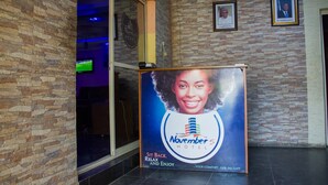 A hotel lobby with stone walls, a framed portrait, and a poster advertising the hotel. - November 5 Hotel Lagos (Lagos)