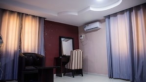 A room with a black leather chair, a small table, a mirror, and an air conditioning unit on the wall. - November 5 Hotel Lagos (Lagos)