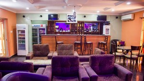 A bar area with seating, a refrigerator, and shelves with bottles. - November 5 Hotel Lagos (Lagos)