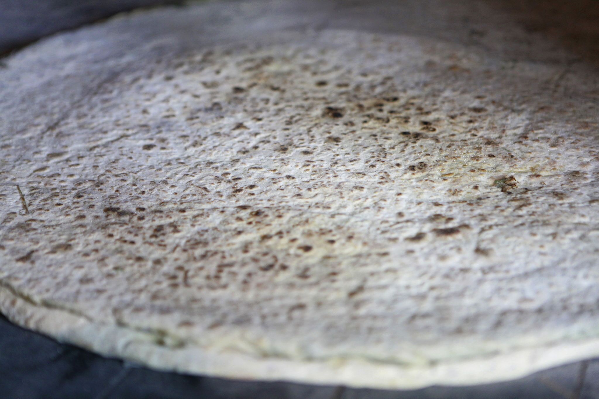Nahaufnahme eines Fladenbrotes mit rauer Oberfläche.