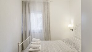 A bedroom with a bed, a window with sheer curtains, a bedside lamp, and a folded towel on the floor. - Apartment in Gata near Adriatic Sea (Gata)
