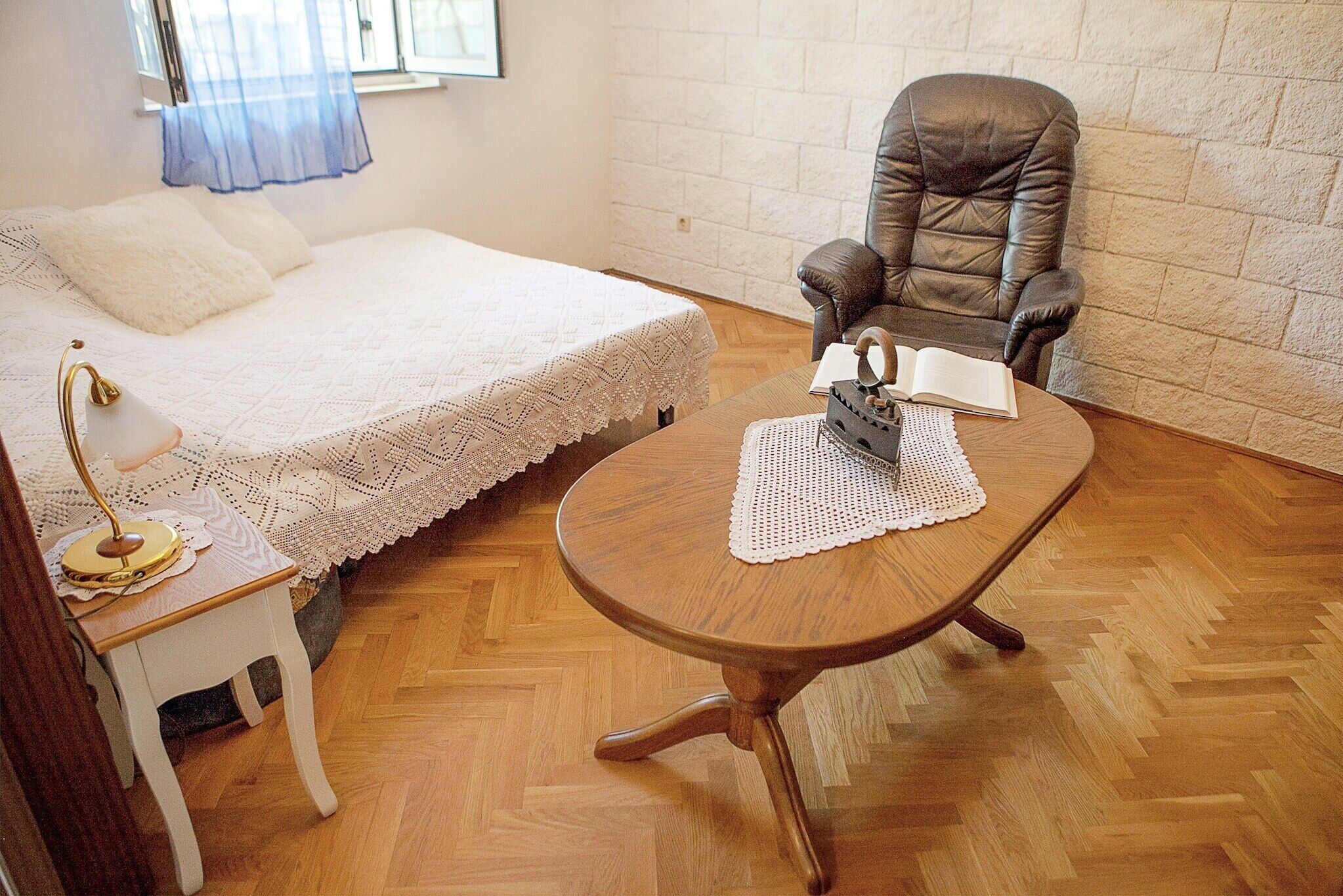 Una camera da letto con un letto, una sedia, un tavolino e una lampada.
