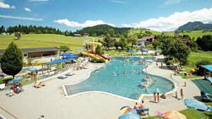 Ein Schwimmbeckenbereich mit mehreren Wasserrutschen und Liegebereichen.