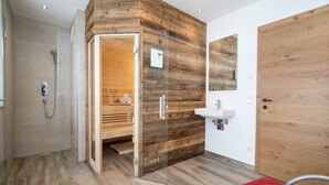 Ein modernes Badezimmer mit einer Wand in Holzoptik, einer Duschkabine aus Glas und einem roten Sessel.