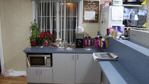 A reception desk with a coffee machine, a clock, and a bulletin board with notices. - Royal Lodge (Absecon)