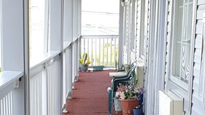 A covered porch with a red carpet, white railings, and potted plants. - Royal Lodge (Absecon)