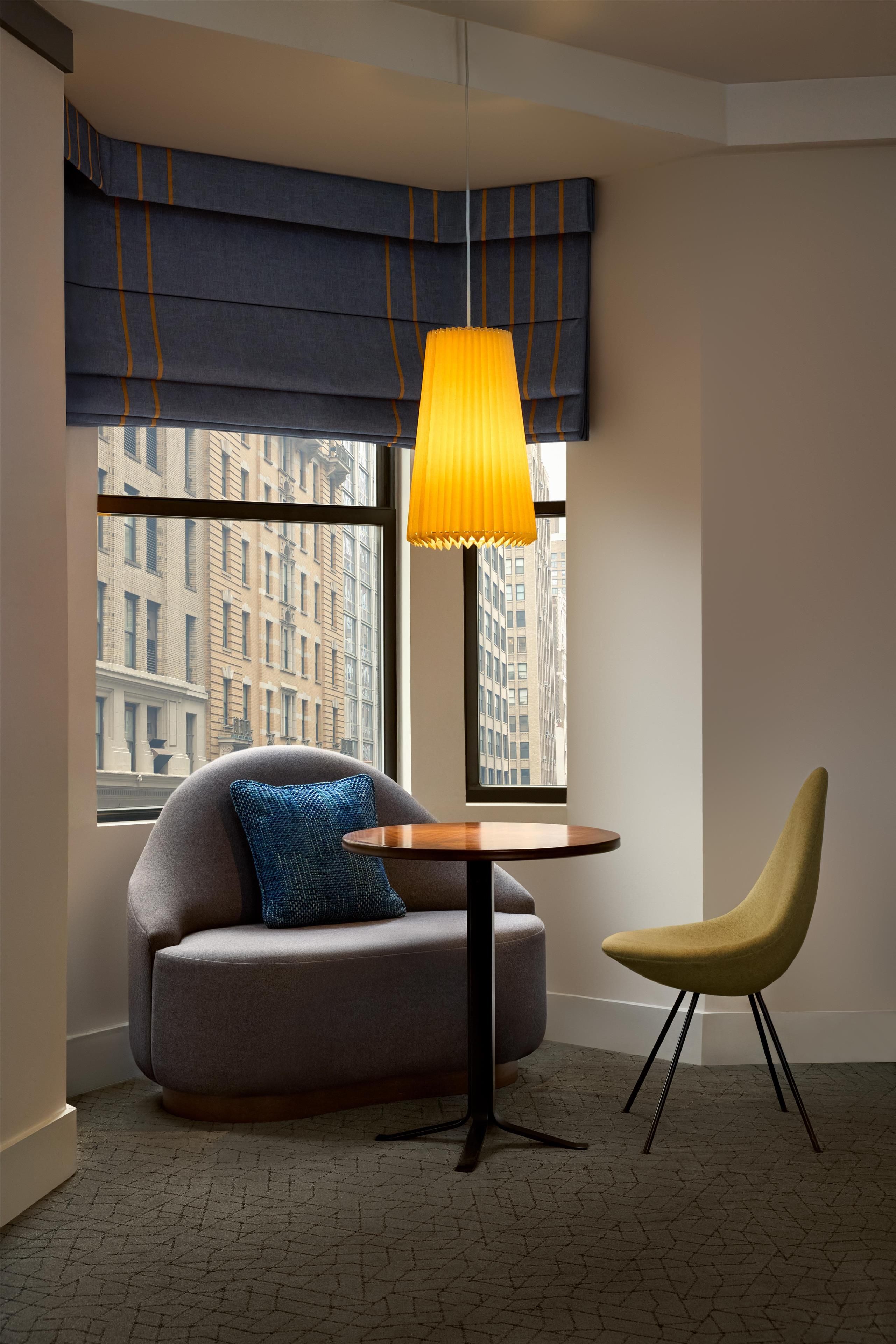Una habitación moderna con un sofá, una mesa redonda y una silla amarilla.