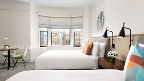 A hotel room with two beds, a desk, and a chair. There is a window with a view of buildings. - Hotel Seville Nomad, in the Unbound Collection by Hyatt (New York)