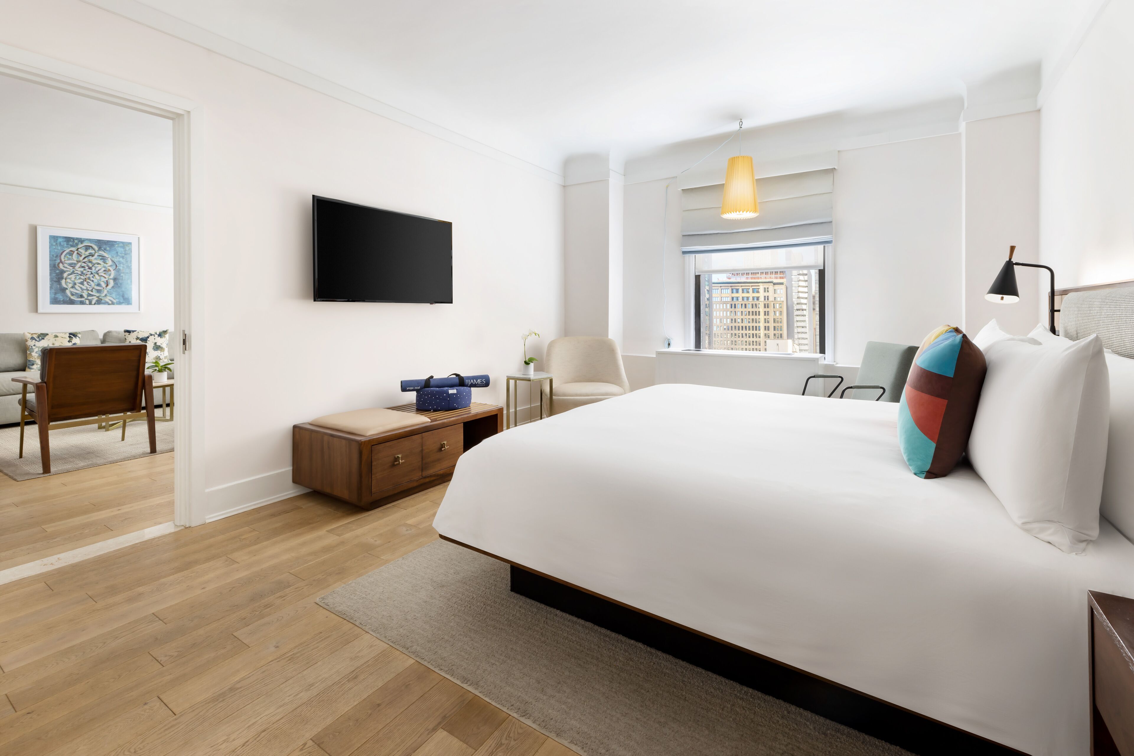 Una habitaci ón de hotel moderna con una cama grande, un televisor de pantalla plana, un escritorio con una silla y una ventana con vista a la ciudad.