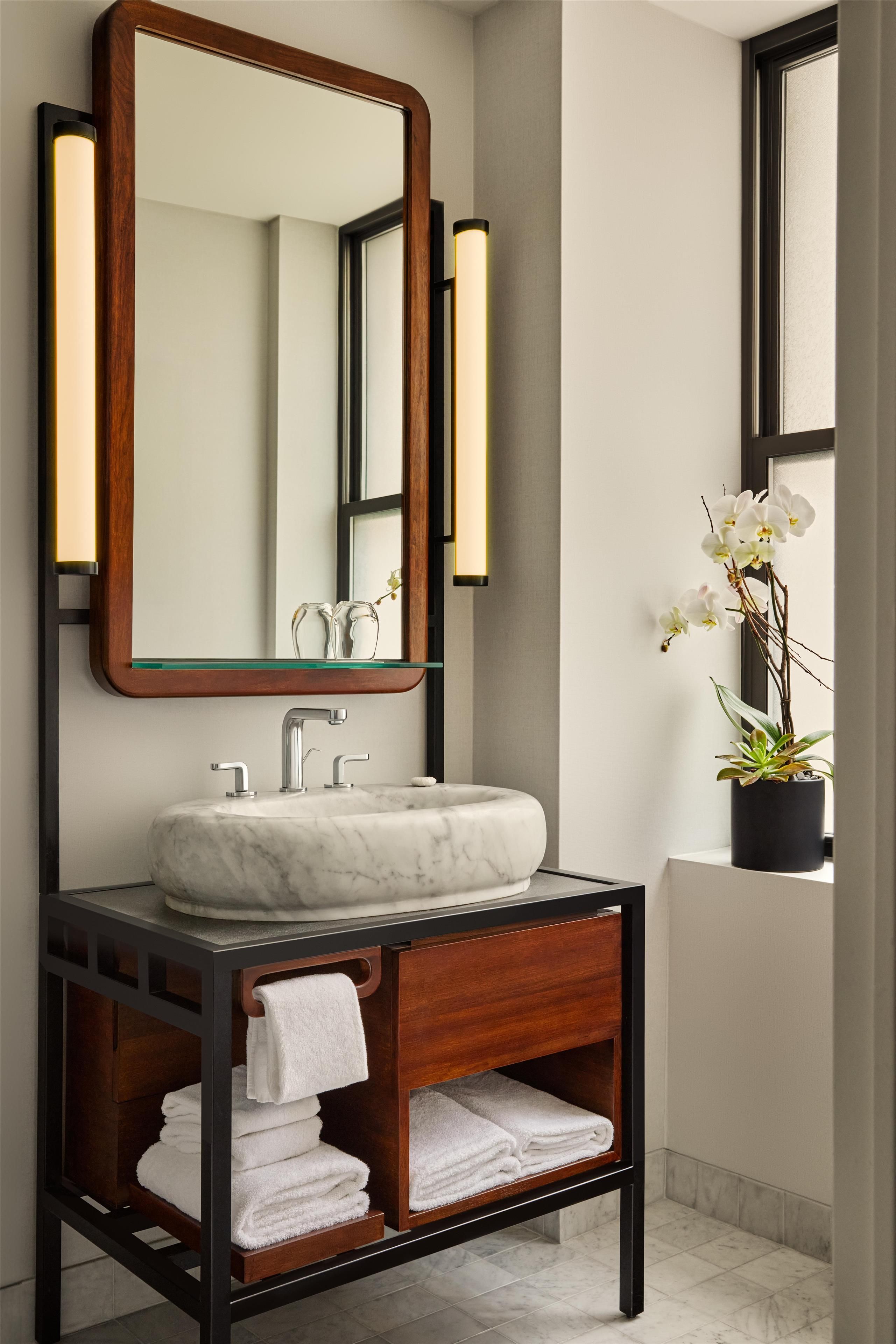 A bathroom with a marble sink, wooden vanity, and a large mirror.