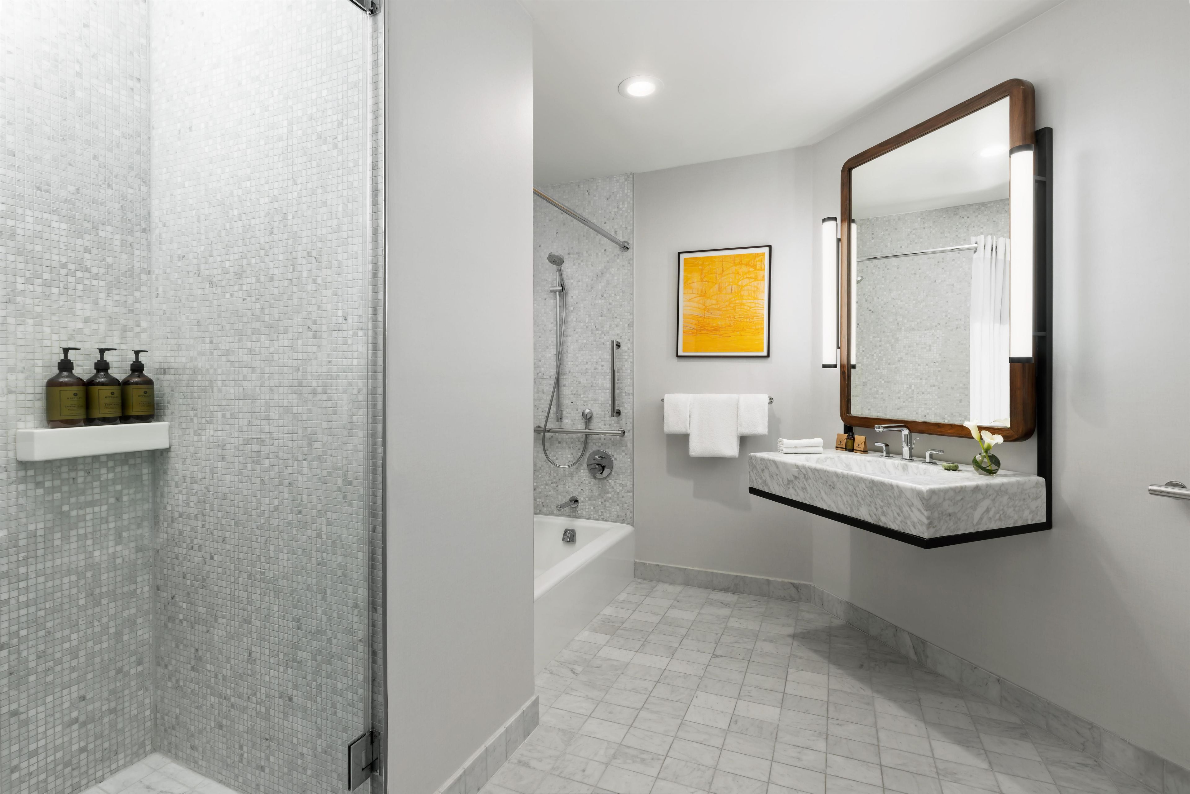 A modern bathroom with a shower, bathtub, and a large mirror.