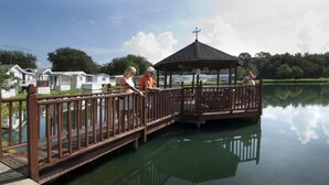 A wooden deck over water with a gazebo, surrounded by mobile homes. - Southern Charm RV Resort (Zephyrhills)