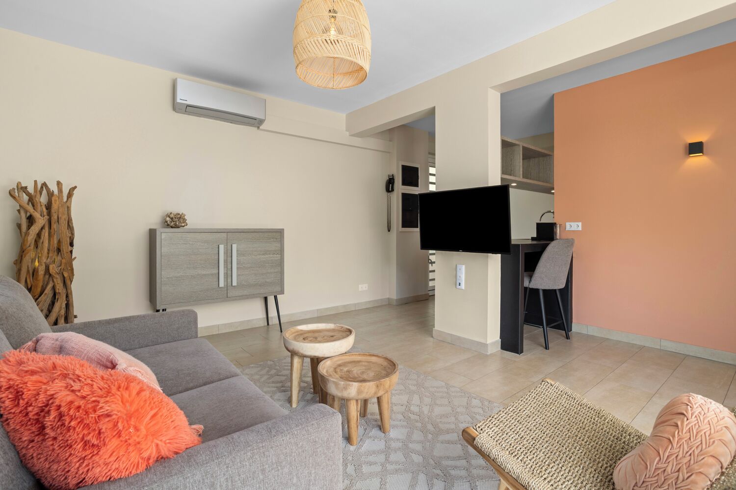 Una sala moderna con un sofá gris, una pequeña mesa de madera y un televisor.