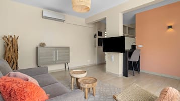 Una sala moderna con un sofá gris, una pequeña mesa de madera y un televisor.