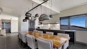 Una cocina moderna con una mesa y sillas de madera, un ventanal y vistas al cielo.