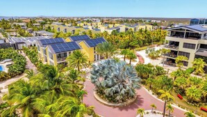 Un resort con varias edificaciones, palmeras y un espacio circular central con un árbol singular.