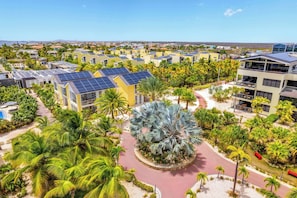 A resort with multiple buildings, palm trees, and a central circular area with a unique tree. - Delfins Beach Resort Bonaire, Tapestry Collection by Hilton (Kralendijk)