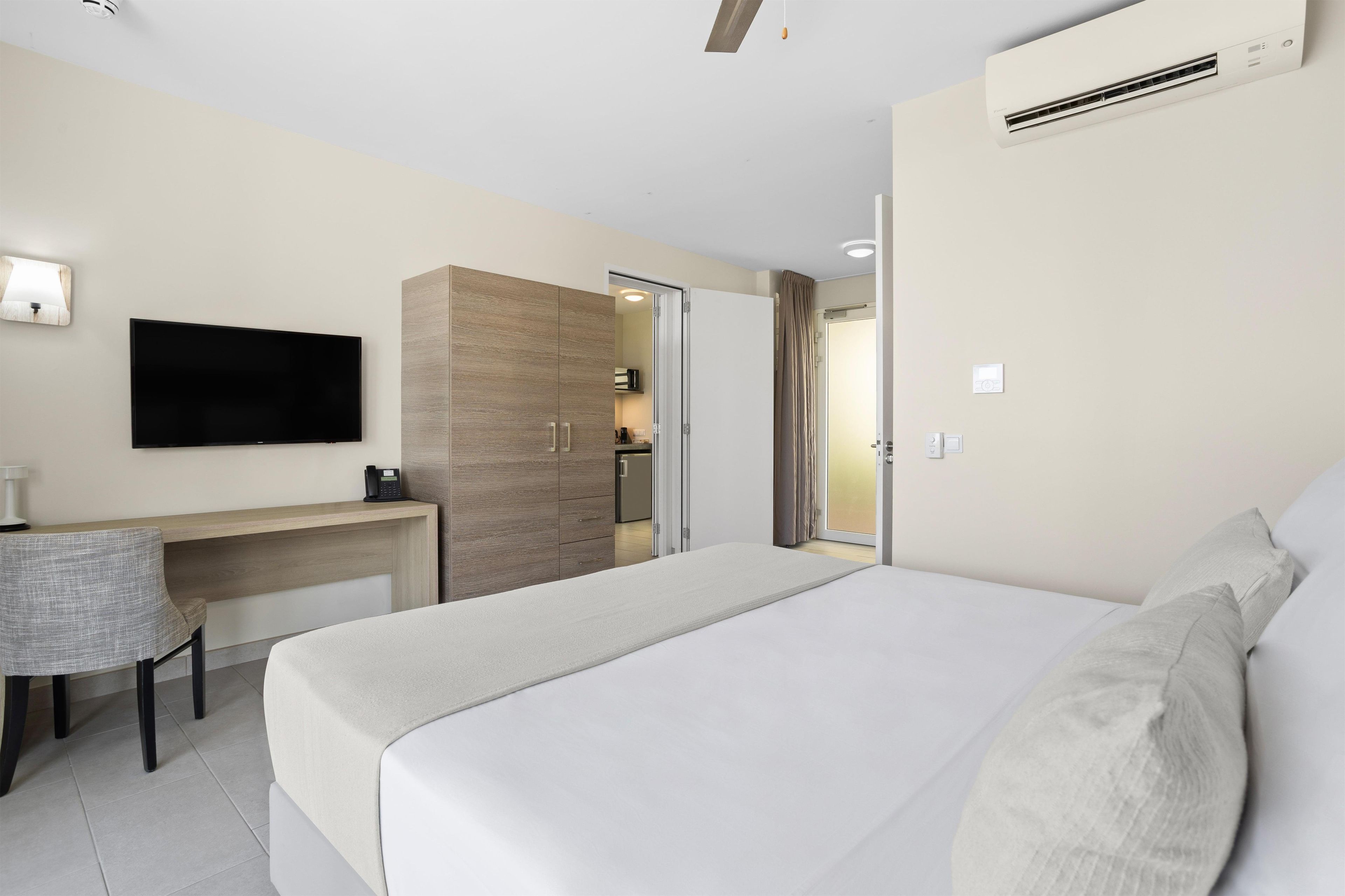 Une chambre d’hôtel équipée d’un lit, d’un bureau, d’une chaise, d’une télévision et d’un appareil de climatisation.