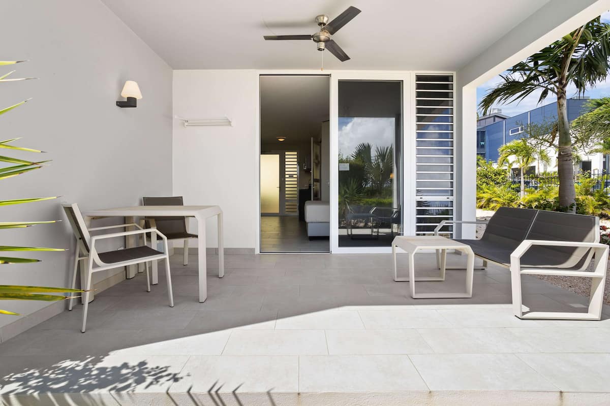 A modern outdoor living area with a ceiling fan, a table with chairs, and a sofa.