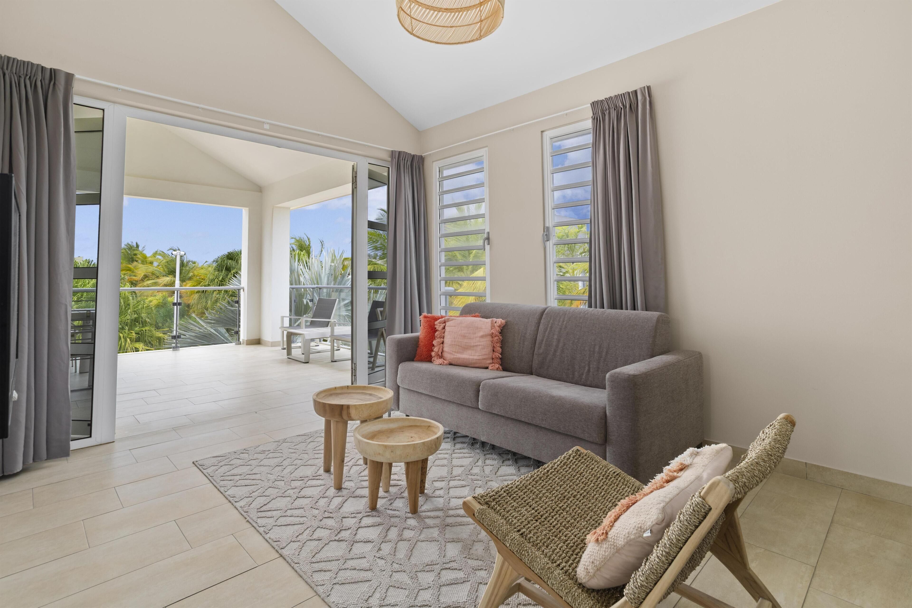A modern living room with a grey sofa, a wicker chair, and a small table.