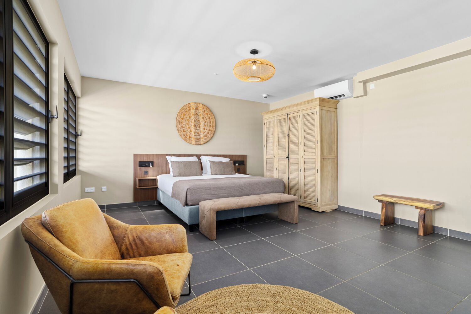 A modern bedroom with a bed, a chair, a bench, and a wardrobe.