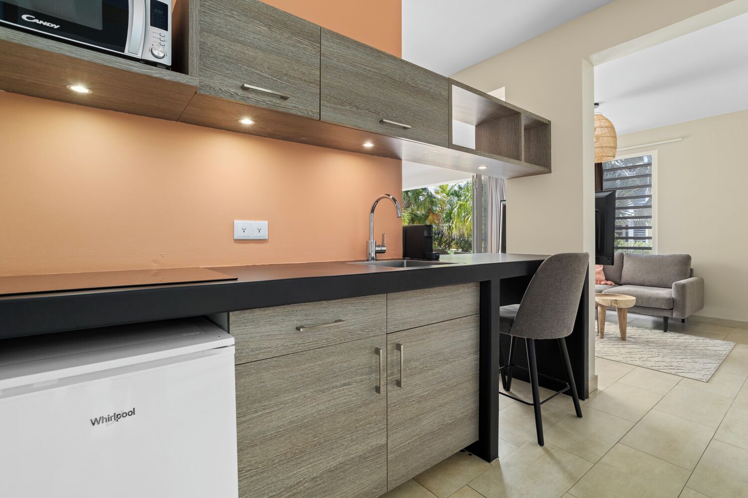 A modern kitchen with a built-in microwave, a sink, and a bar area.