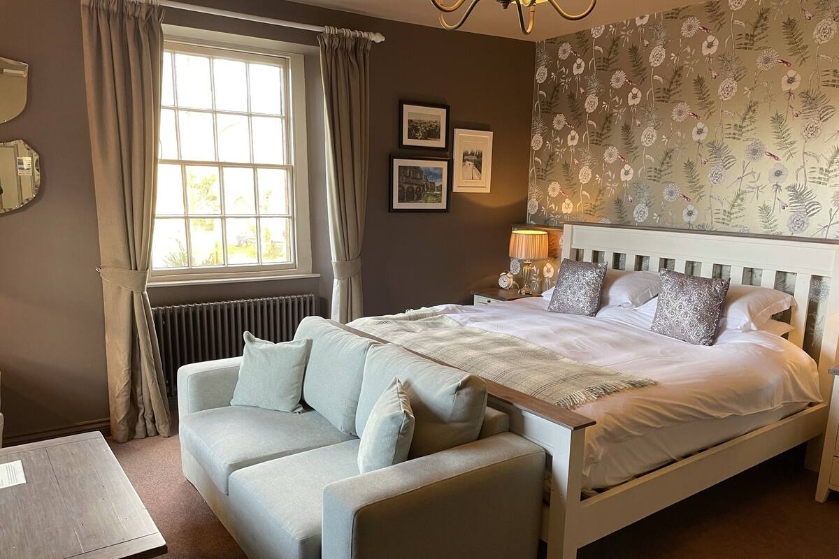 Ein Schlafzimmer mit Bett, Sofa, Nachttisch, Lampe und Heizkörper.