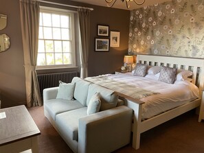 Ein Schlafzimmer mit Bett, Sofa, Nachttisch, Lampe und Heizkörper.