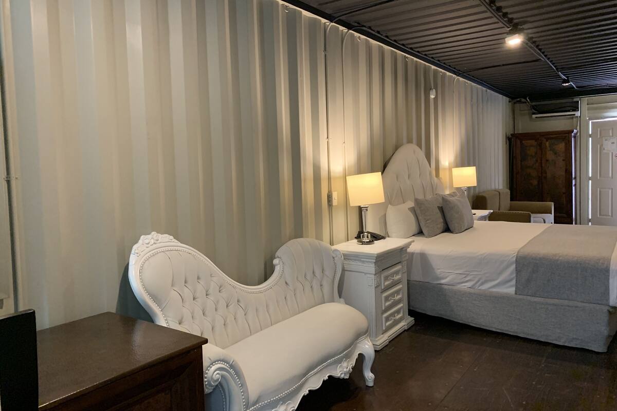 Une chambre d’hôtel avec un grand lit, un petit canapé, une table de chevet avec des lampes et une armoire.