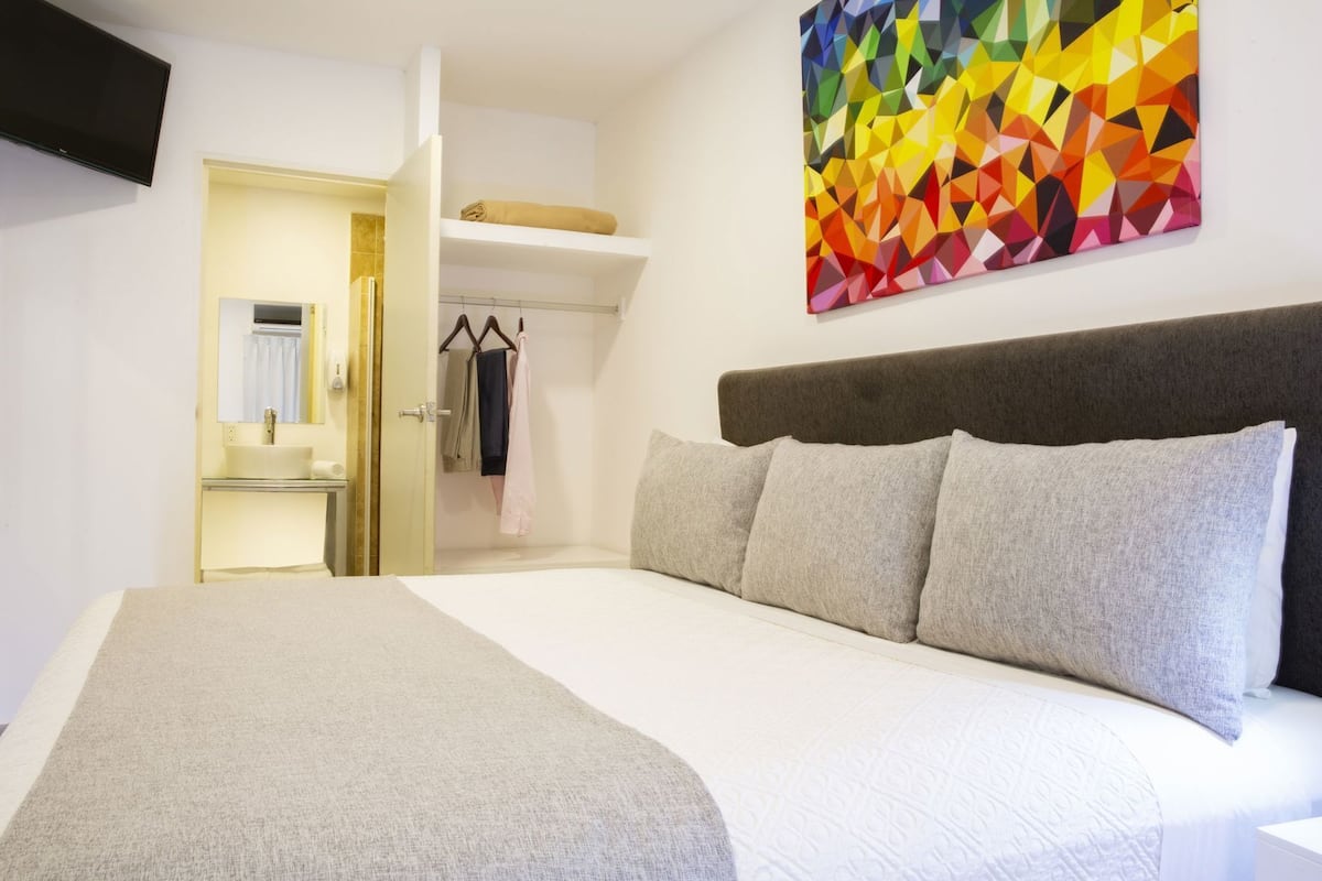 Une chambre d’hôtel avec un lit, un tableau, une armoire et une salle de bain.