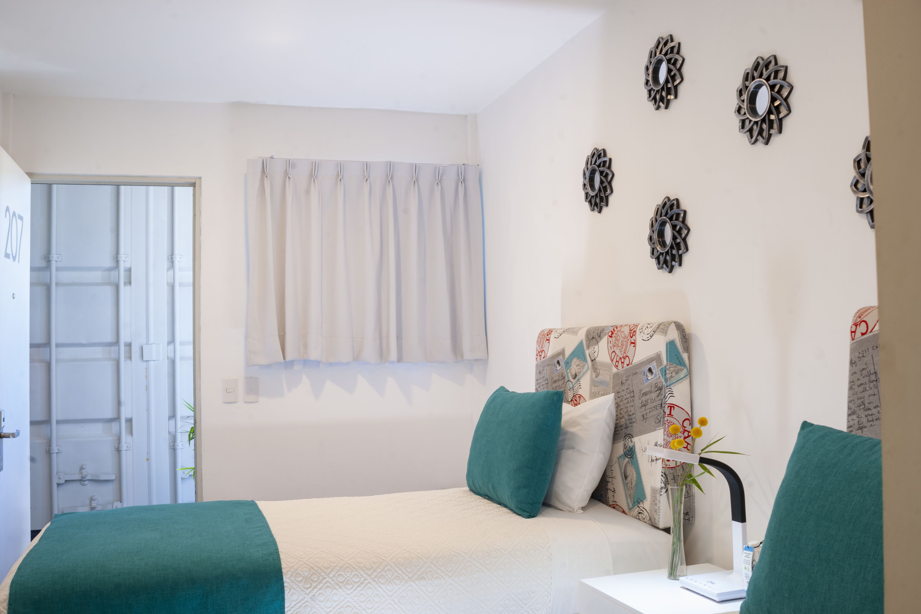 A bedroom with a bed, a desk, and a window with curtains.