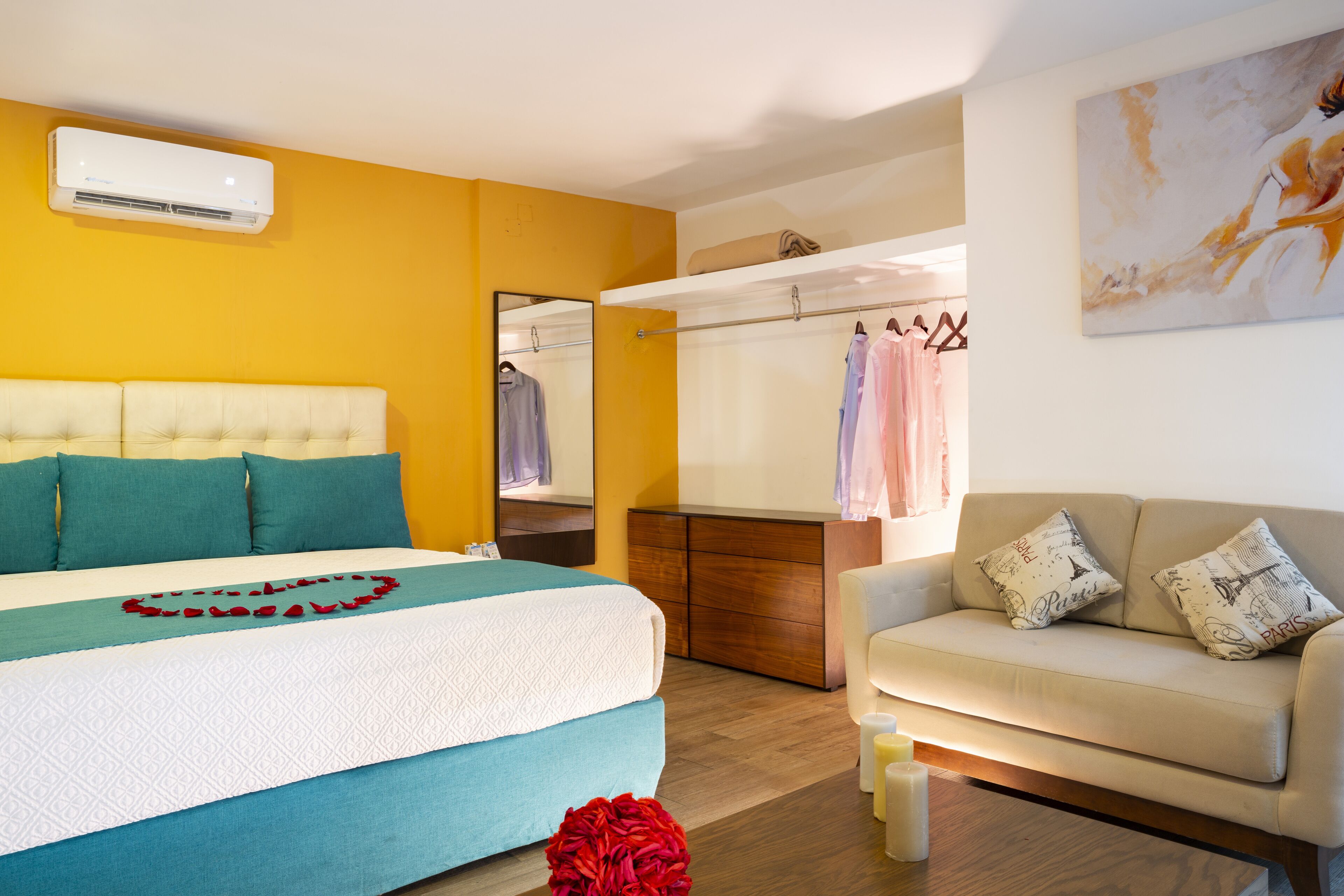 A bedroom with a bed, a sofa, a wardrobe, and a mirror.