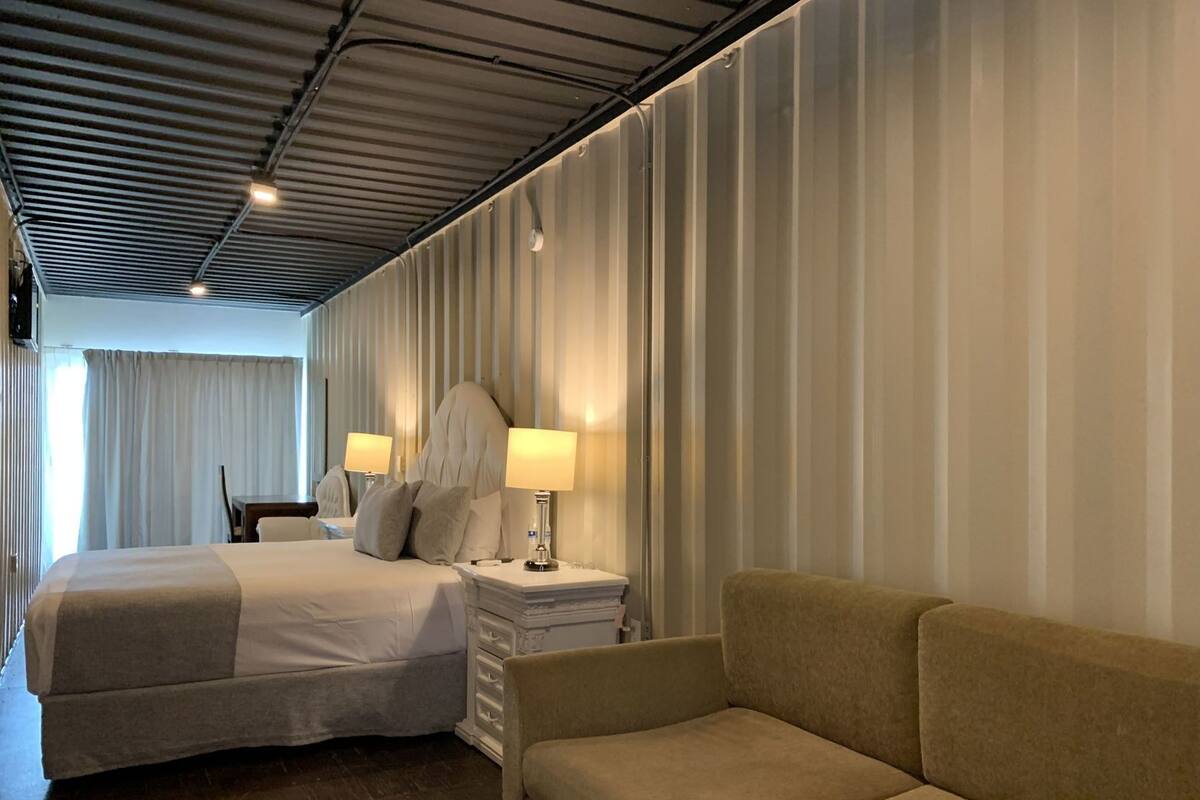 Une chambre d’hôtel avec un lit, un canapé, une table de chevet et un miroir.