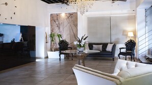 A spacious lobby with a chandelier, a reception desk, a sofa, and a coffee table. - Container Inn Hotel Aeropuerto (Puerto Vallarta)