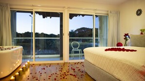 A bedroom with a large sliding glass door leading to a balcony, a bed with rose petals, and a white bathtub. - Container Inn Hotel Aeropuerto (Puerto Vallarta)