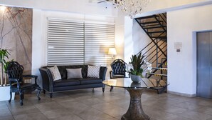 A modern lobby with a chandelier, a staircase, a sofa, and a coffee table. - Container Inn Hotel Aeropuerto (Puerto Vallarta)
