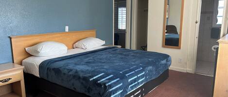 A bedroom with a bed, a nightstand, a dresser, and a mirror.
