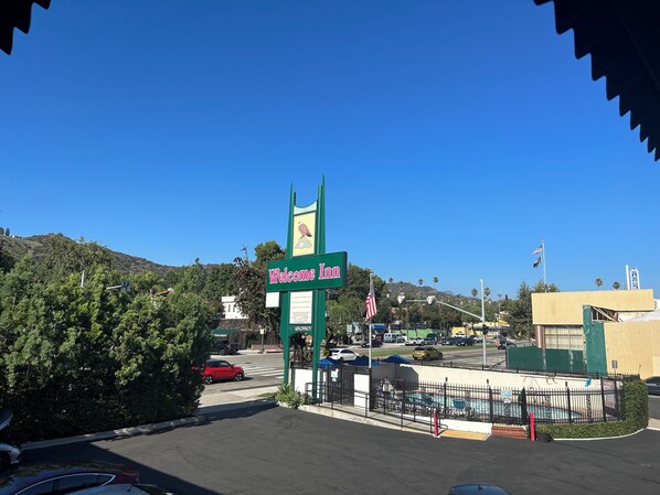 A "Welcome Inn" sign with a mountain backdrop, a fenced pool area, and a clear blue sky.
