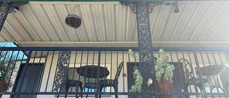 A building with a sign reading "OFFICE" and a covered balcony area with chairs and potted plants.