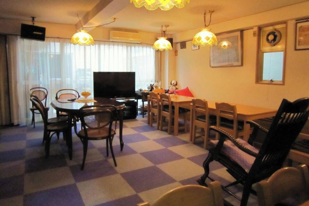 Ein Wohnzimmer mit Schachbrettmuster-Boden, einem Esstisch, Stühlen, einem Fernseher und dekorativen Lampen.
