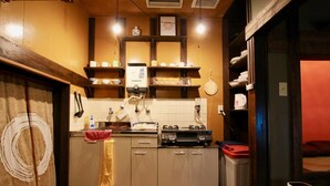 A compact kitchen with wooden cabinets, a built-in oven, and a coffee machine. - Kyoto Traditional Machiya House (Kyoto)