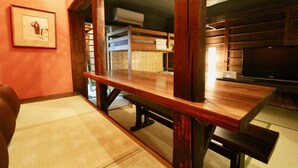 A wooden dining table with benches, a framed picture on the wall, and a television in the room. - Kyoto Traditional Machiya House (Kyoto)